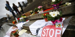 vor dem Kölner Dom liegen Blumen und Stopp-Schilder