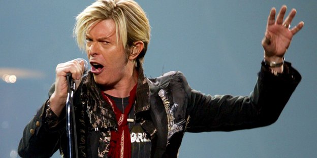 David Bowie gestikuliert bei einem Auftritt.