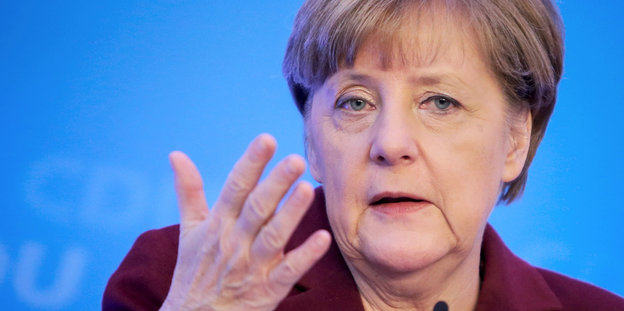 Merkel während einer Rede vor blauem Hintergrund
