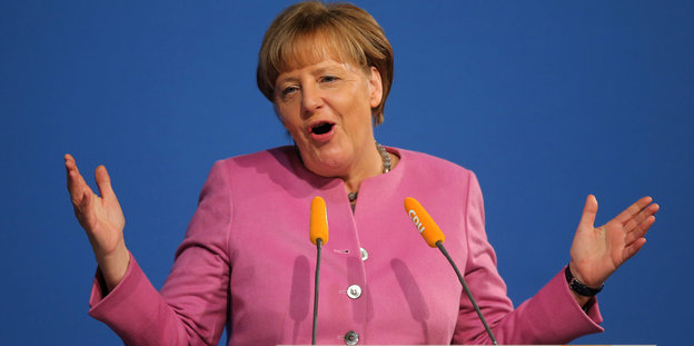 Angela Merkel macht ein überraschtes Gesicht während einer Podiumsrede