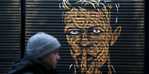 Ein Mann läuft vor einem Portrait von David Bowie