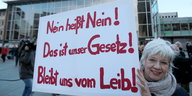 Frau demonstriert mit einem Schild vor dem Kölner Hauptbahnhof. Auf dem Schild steht "Nein heißt Nein!""