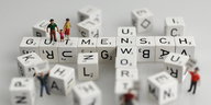 Würfel mit Buchstaben formen „Gutmensch“ und „Unwort“ darauf kleine Figuren von Menschen