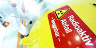Auf einer gelben Mülltonne steht auf einem roten Streifen: Radioaktiv Abfall, brennbar