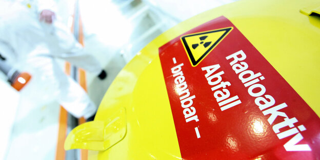 Auf einer gelben Mülltonne steht auf einem roten Streifen: Radioaktiv Abfall, brennbar