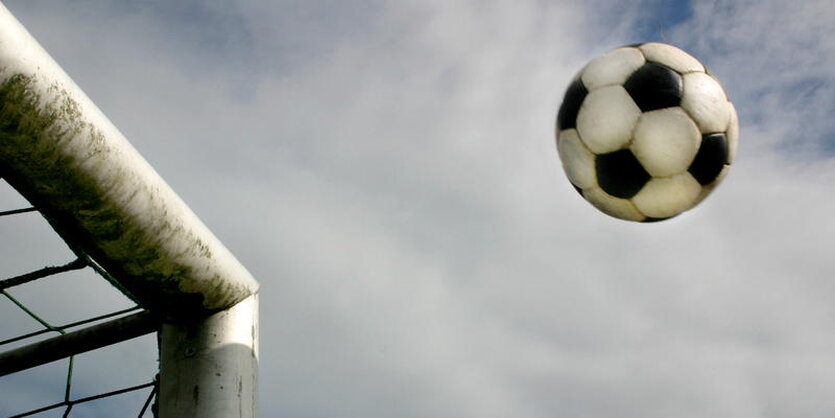 Ein Fußball fliegt in ein Tor.