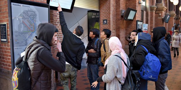 Gruppe von Flüchtlingen schaut auf eine Anzeigetafel im Kopenhagener Bahnhof