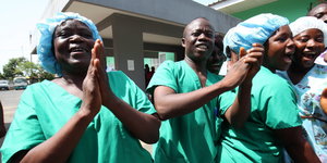 Ärzte freuen sich in Liberia über den Sieg über die Ebolaepidemie. Sie lächeln und klatschen in die Hände.