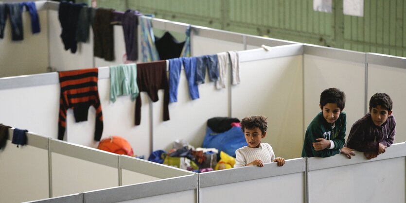 Kinder gucken über Trennwände in der Notunterkunft im Berliner Flughafen Tempelhof