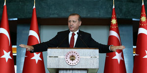 Recep Tayyip Erdogan steht an einem Rednerpult zwischen türkischen Fahnen.