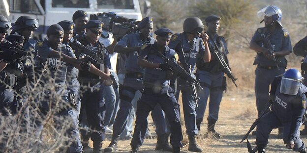 Eine Gruppe von Polizisten richtet ihre Waffen auf Minenarbeiter, die im Bild aber nicht zu sehen sind