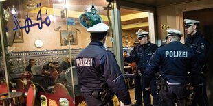 Mehrere Polizisten vor dem Eingang zu einem Lokal.