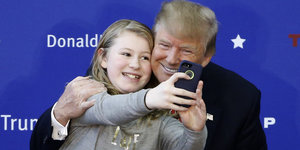 Donald Trump posiert mit einem jungen Fan, um ein Selfie zu machen.