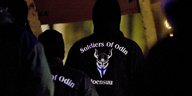 Männer stehen im Dunkeln in einer finnischen Stadt. Auf dem Rücken ihrer Jacken steht „Soldiers of Odin“