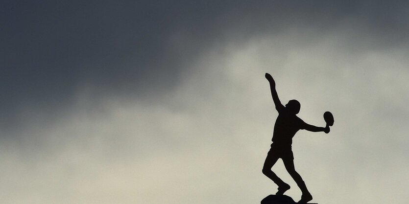 Schattenriss eines Tennisspielers vor wolkenverhangenem Himmel