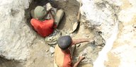 Aus der Vogelperspektive sind zwei Männer zu sehen, die in einer Mine arbeiten.