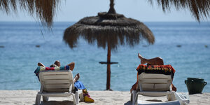 Zwei Touristen liegen in Tunesien am am Strand.