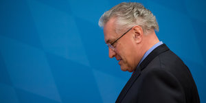 Joachim Herrmann im Profil vor blauem Hintergrund, er schaut nach unten
