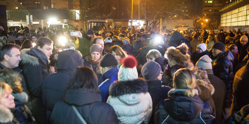 Menschen stehen im Dunkeln auf einer Demonstration.