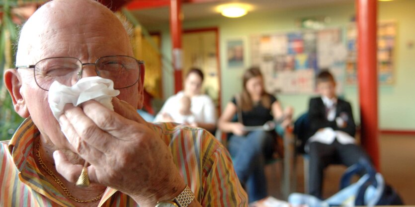 Mann mit Brille putzt seine Nase.