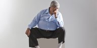 Ein dicker Mann sitzt auf einem Hocker
