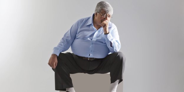 Ein dicker Mann sitzt auf einem Hocker