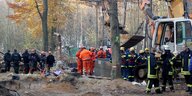 Polizisten und Feuerwehrleute bei einem Bagger im Wald