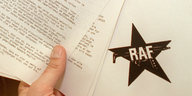 eine Hand hält Papierblätter. Auf einem ist ein schwarzer Stern zu sehen, auf dem die Buchstaben „RAF“ stehen