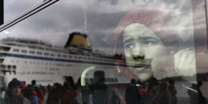 Ein Junge schaut aus einem Busfenster, in dem sich ein großes Schiff spiegelt