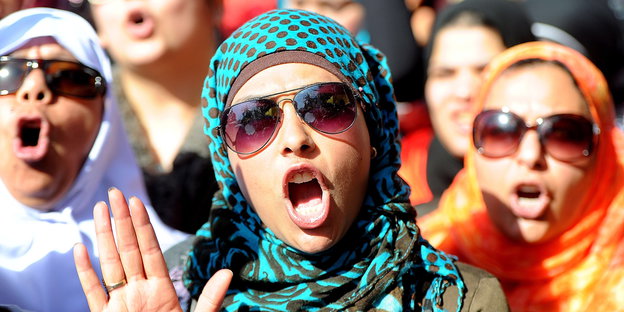 Drei ägyptische Frauen mit bunten Kopftüchern und Sonnenbrillen rufen Sprüche in einer Menge auf dem Tahrir-Platz.