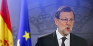 Rajoy mit offenem Mund neben einer spanischen und einer EU-Flagge