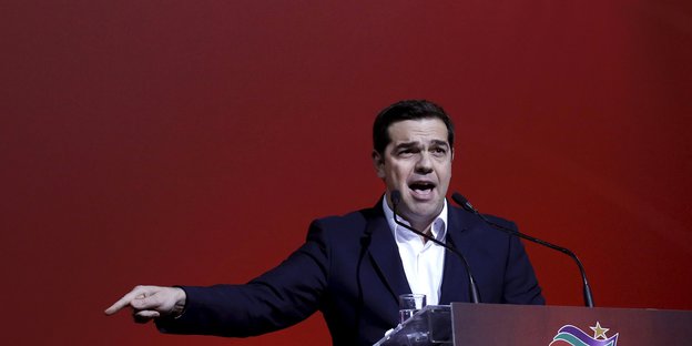 Alexis Tsipras am Rednerpult, mit seinem Finger in Richtung Boden zeigend.