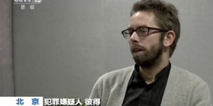 Ein Videostandbild zeigt einen Mann mit Bart und Brille, chinesische Schriftzeichen sind zu sehen