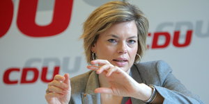 eine gestikulierende Julia Klöckner vor roten und grauen CDU-Schriftzügen