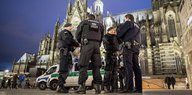 Eine Gruppe Polizist_innen steht am Abend am Kölner Hauptbahnhof