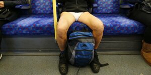 Gespreizte Männerbeine in der U-Bahn. Der Mann ist nur mit Unterhose bekleidet.