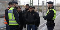 Zwei schwedische Polizisten reden mit einer Gruppe von Männern am Bahnhofsgleis