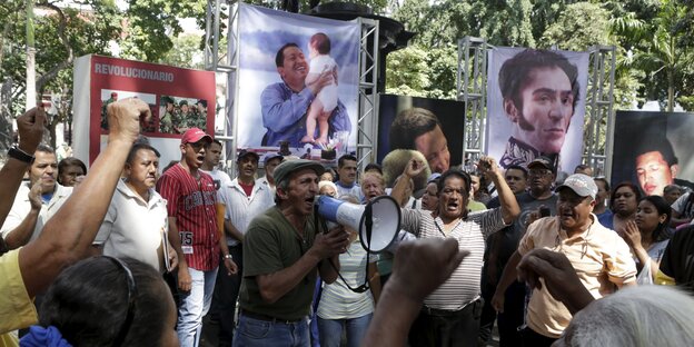 Chavistas auf der Plaza Bolivar vor den Portraits ihrer Helden - Simón Bolivar und Hugo Chávez.