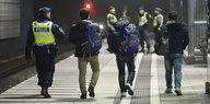 Ein Polizist eskortiert drei Flüchtlinge