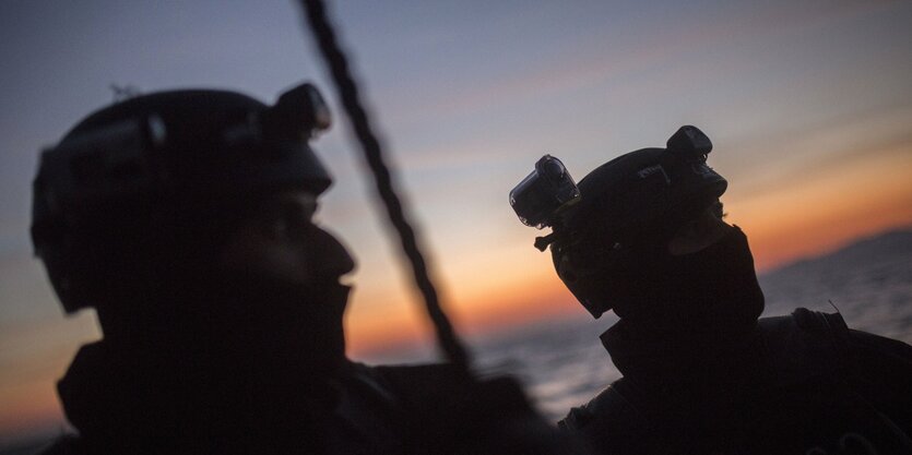 Zwei Männer in Unform blicken auf das Meer.