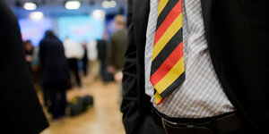 Vor dem Bauch eines Mannes hängt eine schwarz-rot-goldene Krawatte.