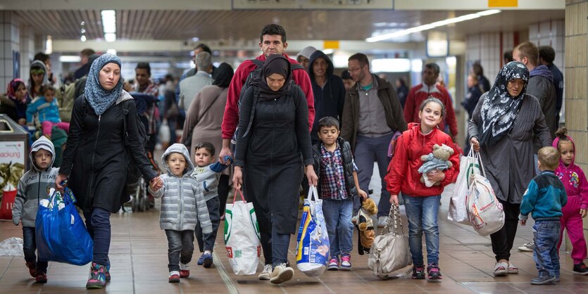 Männer Frauen und Kinder laufen mit Tüten in der Hand nebeneinander her