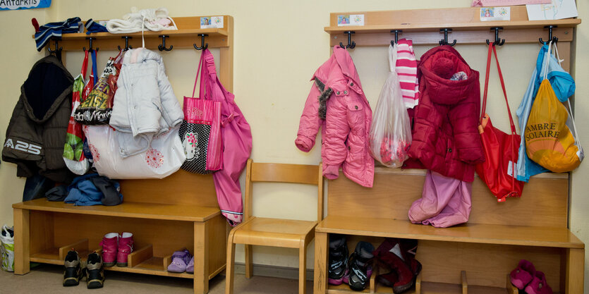 Kinderjacken und -taschen hängen an einer kleinen Garderobe.