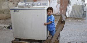 Ein kleiner Junge umarmt eine Waschmaschine