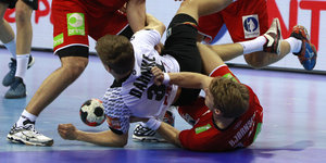 Mehrere Handballer kämpfen um den Ball, einige liegen fast am Boden