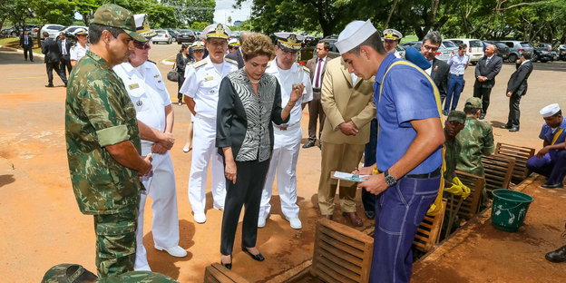 Brasiliens Präsidentin Rousseff, umgeben von Uniformierten, alle schauen nach unten.