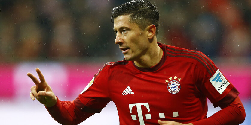 Bayerns Fußballspieler Lewandowski zeigt ein Peace-Zeichen auf dem Platz.