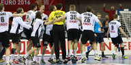 Die Handballer der deutschen Nationalmannschaft stehen auf dem Spielfeld im Kreis und umarmen sich.