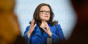 Frau mit Brille und langen dunklen Haaren - es ist Arbeitsministerin Nahles - gestikuliert bei einer Rede