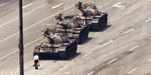 Ein Mann steht auf einer mehrspurigen Straße vor der drei Panzern.